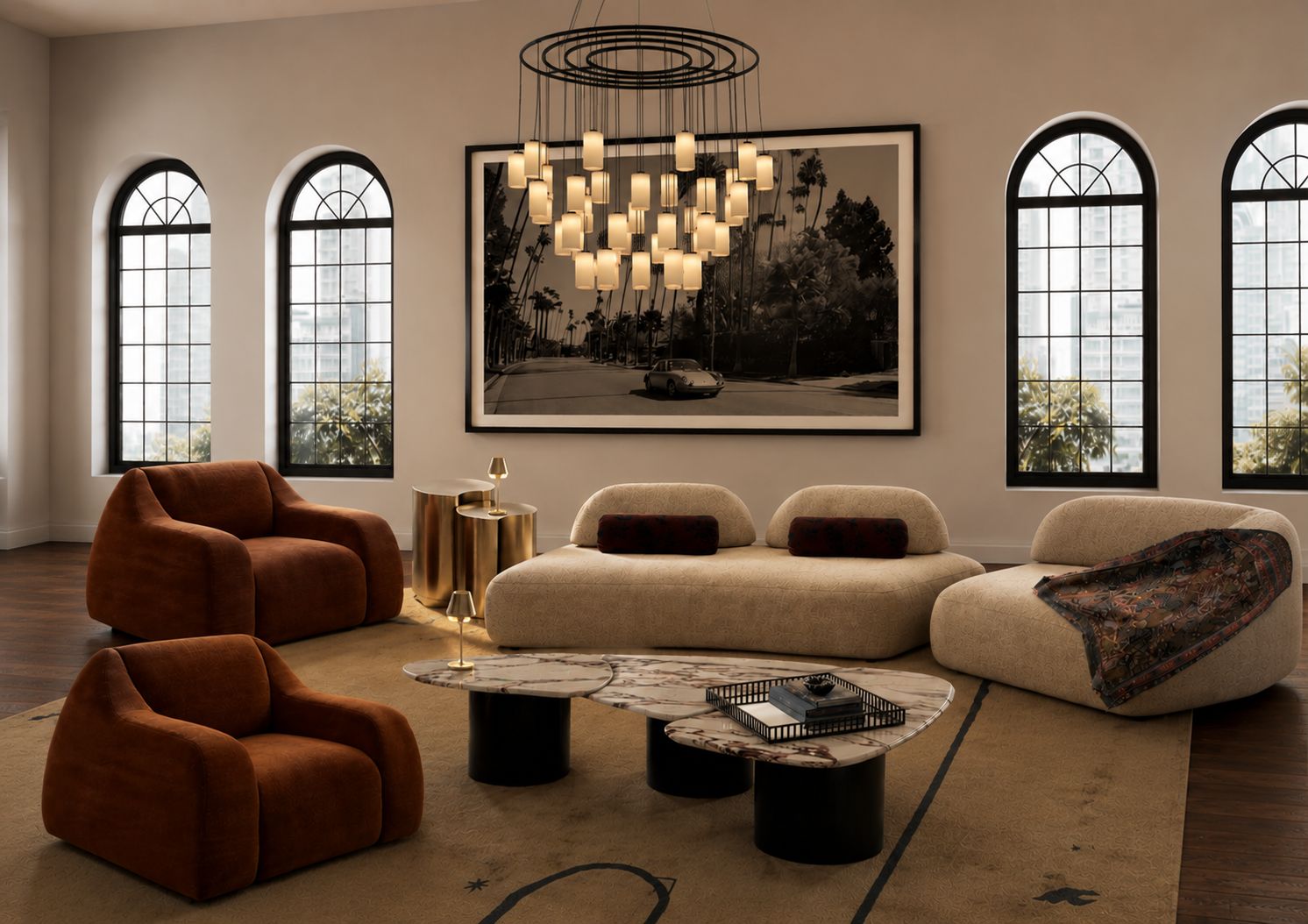 A living room with terracotta velvet armchairs, a cream modular sofa and marble coffee tables beneath a framed black-and-white palm-lined cityscape.